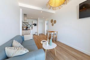 ein Wohnzimmer mit einem blauen Sofa und einem Tisch in der Unterkunft Les Pieds Dans L'Eau - Appartment 2 - Vue mer in Cancale