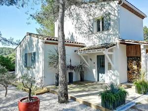 Una casa blanca con un árbol delante. en Villa de 6 chambres avec piscine privee jardin clos et wifi a Saint Bauzille de Montmel, en Saint-Bauzille-de-Montmel