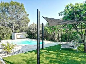 un patio trasero con piscina y sombrilla en Villa de 6 chambres avec piscine privee jardin clos et wifi a Saint Bauzille de Montmel, en Saint-Bauzille-de-Montmel