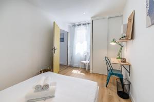 um quarto com uma cama branca e uma cadeira azul em L'ANTHRACITE, apartement rénové, tout confort em Saint-Jacques-de-la-Lande