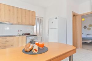 a kitchen with a table with bread and two glasses of orange juice at Marvinas seaside apartments, Earth apartment & Ocean jacuzzi apartment in Kremasti