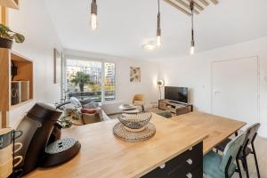 a kitchen and living room with a large wooden table at CÔTÉ RIVIÈRE, appartement T2, terrasse & parking in Rennes