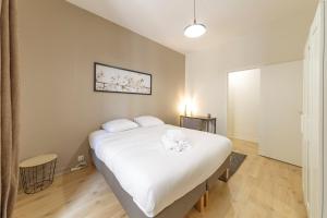 una camera da letto con un grande letto con lenzuola bianche di Saint-Michel - T4 refait à neuf - Hyper centre a Rennes