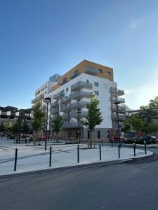 un grand bâtiment blanc avec des arbres devant lui dans l'établissement Le Normand- appartement neuf, 3 chambres, terrasse, à Rennes