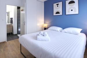 1 dormitorio con 1 cama blanca grande y toallas. en Le Normand- appartement neuf, 3 chambres, terrasse en Rennes