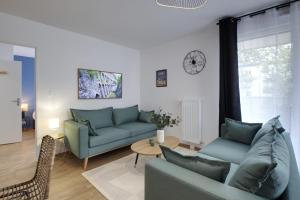 una sala de estar con sofás azules y una mesa. en Le Normand- appartement neuf, 3 chambres, terrasse, en Rennes