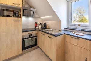 uma cozinha com armários de madeira, um lavatório e uma janela em St-Enogat - Cosy et rénové - Plage à 400m em Dinard