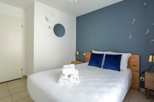 1 dormitorio con 1 cama blanca grande y paredes azules en Le Sévigné - Cosy et calme - balcon et parking, en Cesson-Sévigné