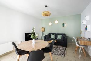 uma sala de estar com uma mesa e um sofá em Le Sévigné - Cosy et calme - balcon et parking em Cesson-Sévigné