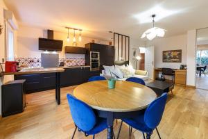 a kitchen and living room with a table and blue chairs at Le Saint Cyr - bel appartement, parking & terrasse in Rennes