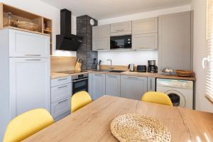 eine Küche mit einem Holztisch und gelben Stühlen in der Unterkunft Le Magellan - logement neuf, parking, grand balcon in Dinard