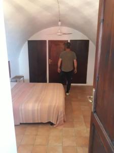 a man walking into a room with a bed at il patio mini appartamento in Pantelleria