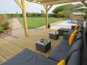 a patio with a blue couch and chairs on a wooden deck at Ochre Cottage in Holsworthy
