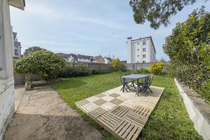 a patio with a table and chairs in a yard at Le Green, appartement rénové, 4 chambres et jardin in Saint-Jacques-de-la-Lande