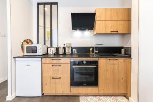 a kitchen with wooden cabinets and a black and white appliance at L'échapée- Bel appartement rénové et proche Gare in Rennes