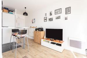 una cucina con TV e 2 sgabelli in una camera di L'Ivoire - Joli appartement - 1 chambre avec a Rennes
