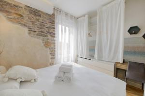 - une chambre avec un lit blanc et un mur en briques dans l'établissement L'Authentique - Joli T2, cosy, proche gare, à Rennes