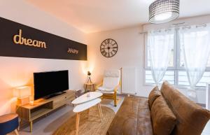 a living room with a couch and a flat screen tv at Le Bacchus parking 1 chambre moderne -Tout confort in Rennes