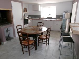 Una cocina con una mesa y sillas de madera. en LOGEMENT 4 PERSONNES, en Gréville-Hague 2 fotos más
