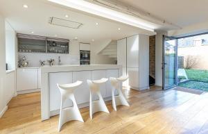 a kitchen with white counters and white stools at Villa Asselin - Belle maison en pierre -4 chambres in Beaussais sur Mer