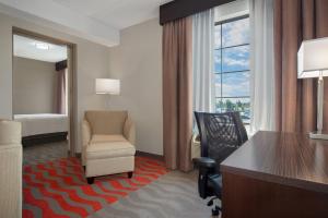 Holiday Inn Express Hotel & Suites Barrie, an IHG Hotel في باري: غرفة في الفندق بها مكتب وكرسي وغرفة نوم