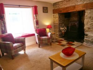 a living room with a stone fireplace and a table and chairs at Rhostwarch Old Farmhouse Eglwyswrw in Eglwyswrw