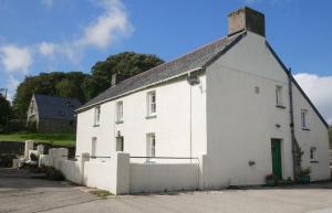 un edificio blanco con una valla delante en Rhostwarch Old Farmhouse Eglwyswrw, en Eglwyswrw