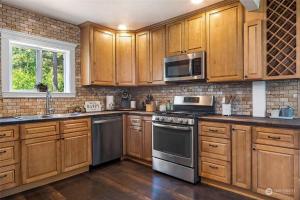 a kitchen with wooden cabinets and stainless steel appliances at Secluded 4BR Nestled in Woods-Hot Tub/Dog Friendly in Friday Harbor