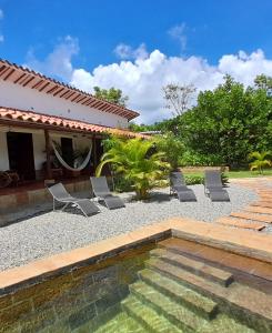 um quintal com piscina e cadeiras e uma casa em Casa Alamanda B&B em Barichara