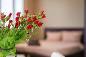 a vase filled with red flowers in a living room at Funky apartment in Studentski Grad in Sofia +3 photos