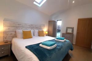 a bedroom with a large bed with towels on it at Umber Cottage in Holsworthy