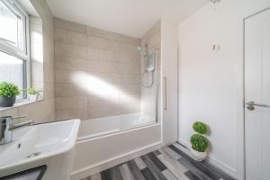 Baño blanco con bañera y lavamanos en Pelshaven Cottage en Cornhill-on-tweed