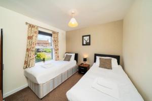 two beds in a room with a window at Pelshaven Cottage in Cornhill-on-tweed