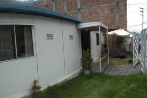 a white house with an umbrella and a patio at Vivienda familiar Doña Marta Churin in Churín