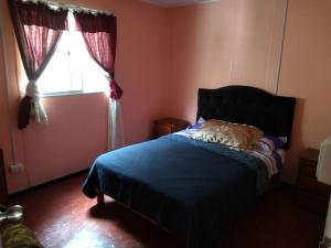 a bedroom with a blue bed and a window at Vivienda familiar Doña Marta Churin in Churín