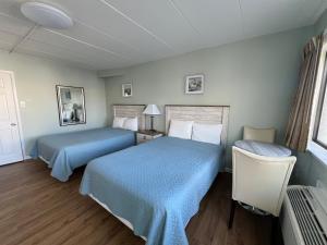 Sand Pebble Motor Lodge في بوينت بليزانت بيتش: سريرين في غرفة الفندق ذات شراشف زرقاء