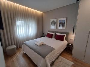a bedroom with a large white bed with red pillows at OPORTO Suites in Moreira +37 photos