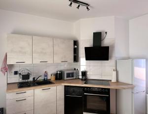 a kitchen with white cabinets and a black appliance at Vila Bösdorf Apartments in Calvörde
