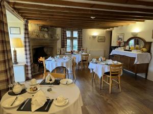a dining room with tables and chairs and a fireplace at Guiting Guest House in Guiting Power