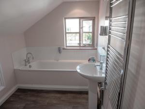 biała łazienka z wanną i umywalką w obiekcie By the River w mieście Glasbury