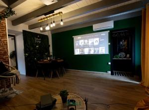 una sala de estar con una pared verde y una pantalla de proyección en MAISON "Jungle House" 90 m2 BILLARD, RÉTROPROJECTEUR, BAR À JEUX , VINYLE, WIFI FIBRE, idéal PRO & FAMILLE à Montbrison, en Montbrison
