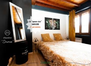 Dormitorio con cama y póster en la pared en MAISON "Jungle House" 90 m2 BILLARD, RÉTROPROJECTEUR, BAR À JEUX , VINYLE, WIFI FIBRE, idéal PRO & FAMILLE à Montbrison, en Montbrison