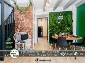 una camera con tavolo e parete verde di MAISON "Jungle House" 90 m2 BILLARD, RÉTROPROJECTEUR, BAR À JEUX , VINYLE, WIFI FIBRE, idéal PRO & FAMILLE à Montbrison a Montbrison