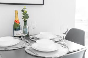 una mesa con platos blancos y una botella de vino en New 2 Bedroom Deluxe Apartment - Parking - Wifi & Netflix - Top Rated - 50C en Sleightholme