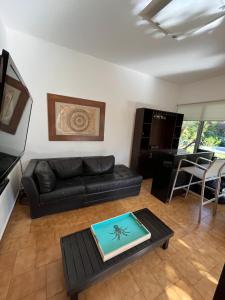 uma sala de estar com um sofá de couro preto e uma mesa em COLIVING em Cuernavaca