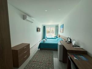 a bedroom with a blue bed and a window at La Bella Guesthouse in St. Julianʼs