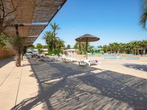 a beach with chairs and an umbrella and a pool at Camping Le Barcarès in Le Barcarès