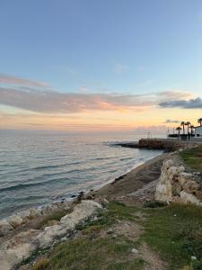 a beach with a pier and the ocean at sunset at Casa del Corso Apartments in Avola