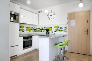 a kitchen with white cabinets and a green stool at ApartamentyPrzyMorzu Apartament z basenem i bawialnią in Kołobrzeg