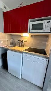 eine Küche mit weißen Geräten und roten Schränken in der Unterkunft appartement en residence au golf in Biscarrosse